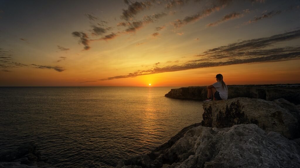 Photo of Person Sitting on Rock During Sunset - Phuket's Best Sunrise and Sunset Viewpoints: Nature's Spectacle